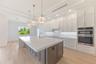 The gourmet kitchen is a true showpiece, featuring full-height custom cabinetry, an oversized 11-foot quartz island with storage on both sides, marble