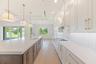 The gourmet kitchen is a true showpiece, featuring full-height custom cabinetry, an oversized 11-foot quartz island with storage on both sides, marble