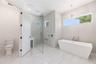 The luxurious primary suite offers a spa-inspired retreat featuring a freestanding soaking tub, oversized walk-in shower with rain head and handheld s