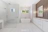 The luxurious primary suite offers a spa-inspired retreat featuring a freestanding soaking tub, oversized walk-in shower with rain head and handheld s