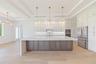The gourmet kitchen is a true showpiece, featuring full-height custom cabinetry, an oversized 11-foot quartz island with storage on both sides, marble