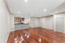 Open-concept living space featuring wood-finish flooring, recessed lighting, crown molding, a kitchen bar with a stone finish, and light wood cabinetr