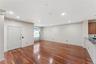 Open-concept living area with polished wood-finish flooring, recessed lighting, crown molding, and a kitchen bar with a granite-style countertop