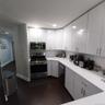 Modern kitchen featuring bright white cabinetry, stainless steel appliances, white countertops, and dark wood-finish flooring