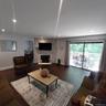 Spacious living area featuring wood-finish flooring, a stone-accented fireplace, and recessed lighting