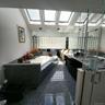 Bathroom featuring multiple skylights, a built-in tub with a stone surround, a glass block wall, and reflective flooring