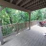 Expansive outdoor deck featuring wood-finish flooring, a full-length perimeter railing, and a covered ceiling structure