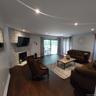 Spacious living area featuring wood-finish flooring, a stacked stone fireplace, recessed lighting, and sliding glass doors opening to an exterior deck