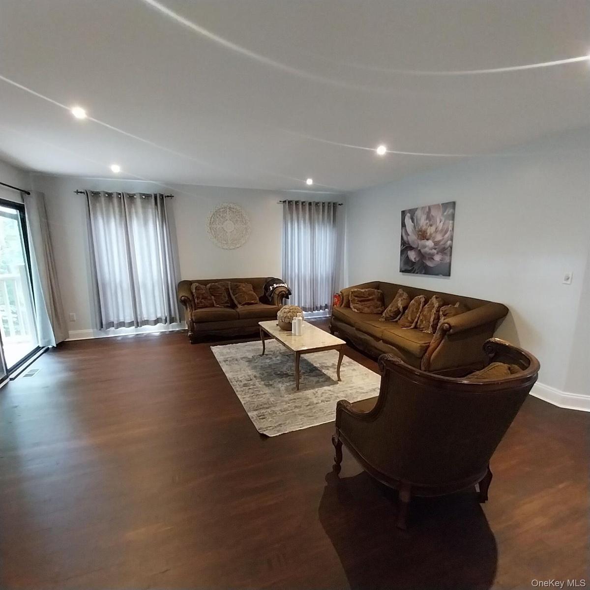 Spacious interior featuring dark wood-finish flooring, recessed lighting, and white baseboards