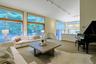 Formal living room with a wall of floor-to-ceiling windows fram picturesque views of the terrace and pond.