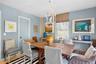 Dining area featuring light blue walls, a white decorative chandelier, a wood-finish table, and a window with blinds