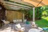Spacious outdoor deck featuring natural wood flooring, a slatted pergola, a decorative privacy screen, a column support, and an attached umbrella for 