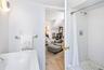 Primary bathroom featuring a white subway tile shower with hexagonal tile flooring, a white porcelain tub, and a chrome towel bar