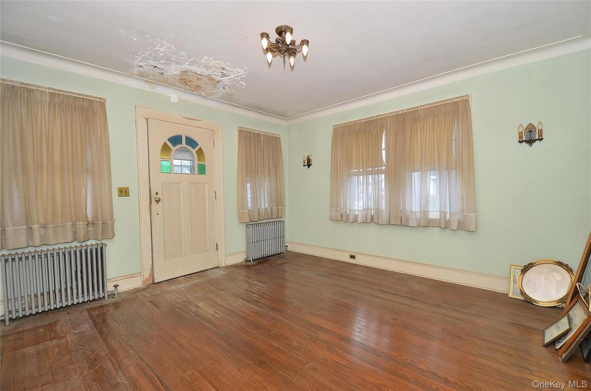 Living Room featuring a solid wood door, hardwood flooring, and crown molding