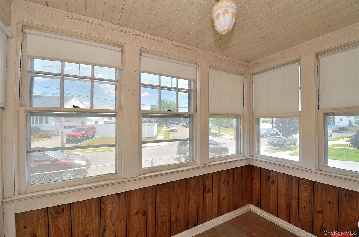 Entry featuring multiple windows with roller shades, wood-finish flooring, and horizontal wood paneling