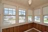 Entry featuring multiple windows with roller shades, wood-finish flooring, and horizontal wood paneling