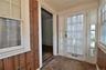 Entry featuring multiple windows with roller shades, wood-finish flooring, and horizontal wood paneling