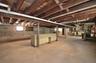 Expansive unfinished basement featuring exposed wood ceiling joists and concrete flooring