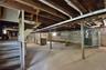 Spacious full basement featuring exposed wood joists, concrete flooring, and a water heater