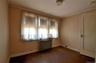 Expansive window framing the wall, wood-finish flooring, baseboard trim, ceiling-mounted light fixture, and solid interior door