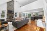 Vaulted ceiling great room featuring a floor-to-ceiling stone fireplace, wood-finish flooring, and a mezzanine overlook