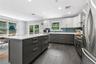 Kitchen featuring a central island with white countertop, stainless steel appliances, dark gray lower cabinetry, and light gray upper cabinetry