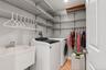 Dedicated laundry room featuring a utility sink, extensive wire shelving, a hanging rod, and tile flooring
