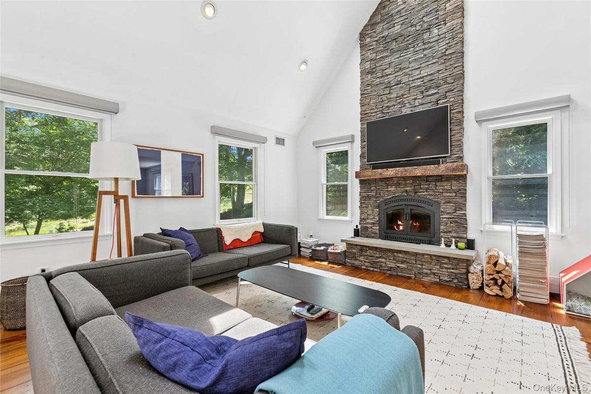 Living area featuring a floor-to-ceiling stone wood fireplace with a wood mantel