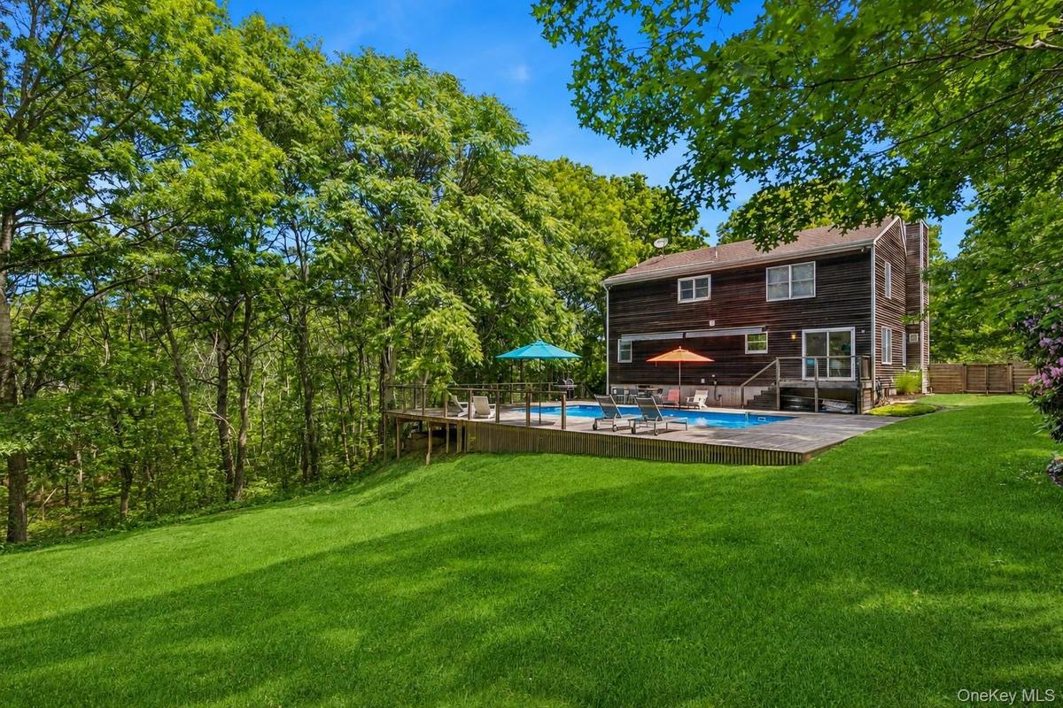Expansive backyard featuring a large green lawn, an in-ground swimming pool, and a surrounding wood deck