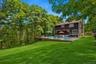 Expansive backyard featuring a large green lawn, an in-ground swimming pool, and a surrounding wood deck
