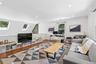 Hardwood flooring, recessed lighting, and skylight windows illuminate this versatile living area featuring a built-in media console and a dedicated de