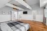Spacious room featuring exposed ceiling beams, wood-finish flooring, vaulted ceilings, and wainscoting