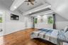 Vaulted ceiling with exposed white beams and a ceiling fan, complemented by warm wood-finish flooring