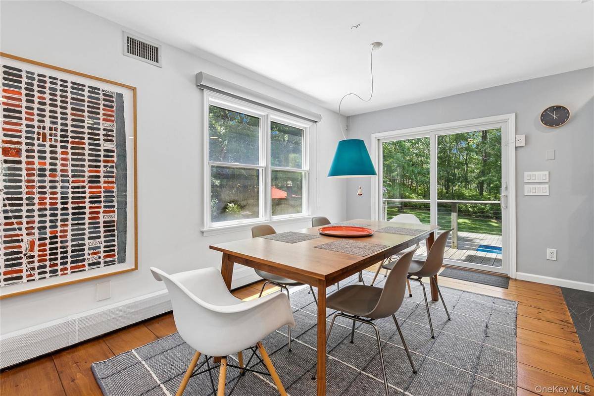 Dining area featuring wood-finish flooring, a contemporary pendant light fixture, and a sliding glass door providing access to an exterior deck