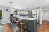 Kitchen featuring a central island with white countertop, two-tone cabinetry, stainless steel appliances, a tile backsplash, and recessed lighting