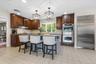 The renovated Chef's kitchen boasts two-tone cabinetry, granite counters, a greenhouse window, pendants over the center island/breakfast bar, stainles