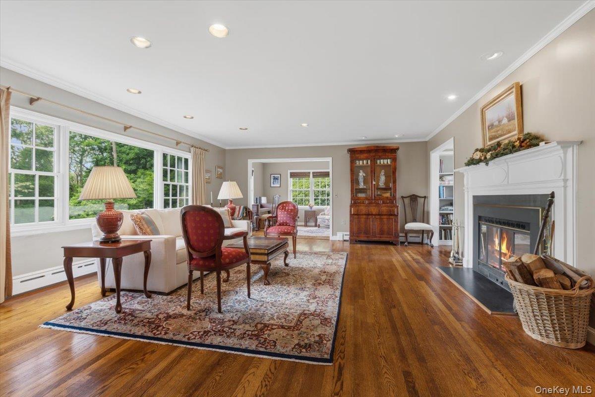 The spacious Living Room offers beautiful views of nature, shiny oak floors, recessed lights and a wood-burning fireplace, as well as a reading nook w