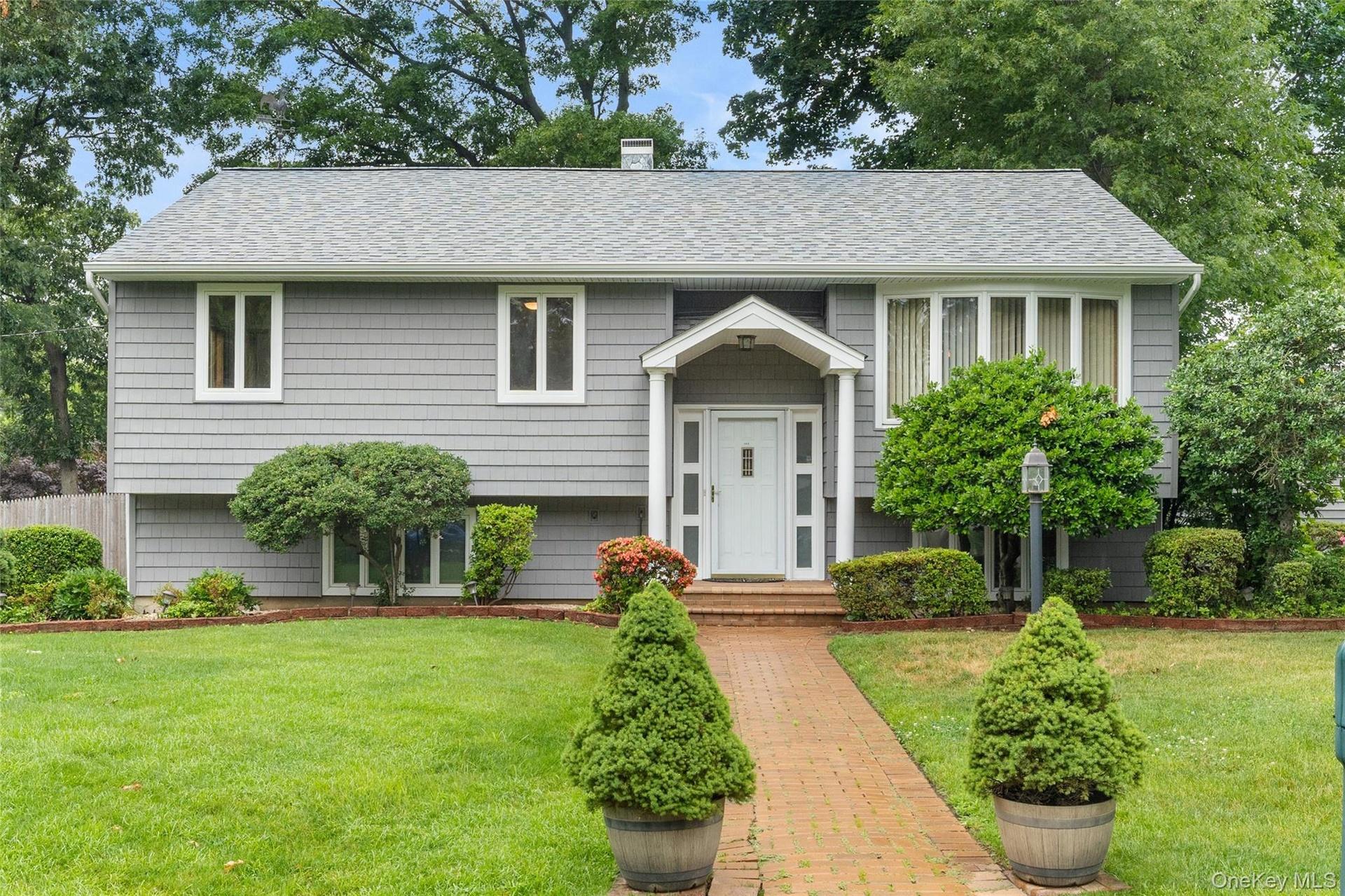 Gray shingle siding exterior featuring a covered entry, white front door, and bay window