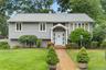 Gray shingle siding exterior featuring a covered entry, white front door, and bay window