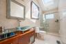 Bathroom featuring tile walls, vanity, a stall shower, a skylight, and light tile patterned floors