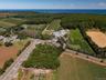 View of property location featuring large plots for crops, rural landscape, and a nearby body of water