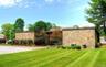Beautiful stone facade with recessed entrance adorned with mature landscaping.