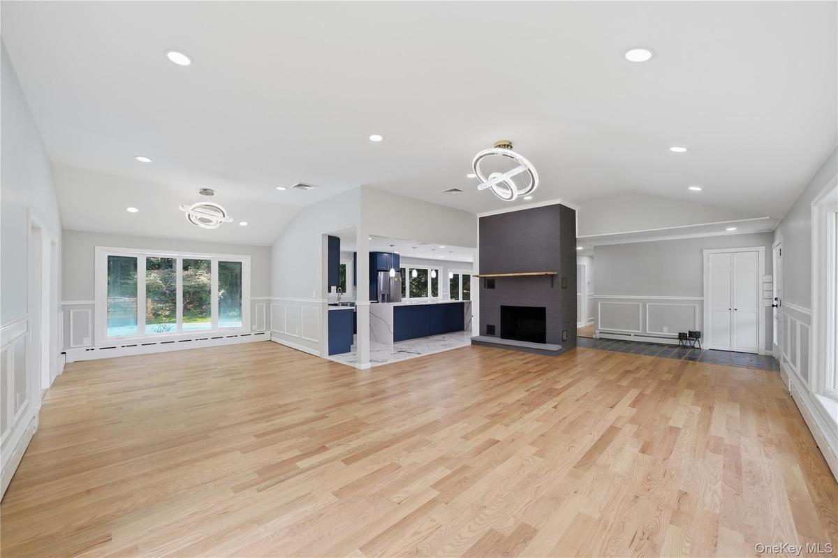 Spacious interior featuring wood-finish flooring, a fireplace with a dark mantel, and recessed lighting