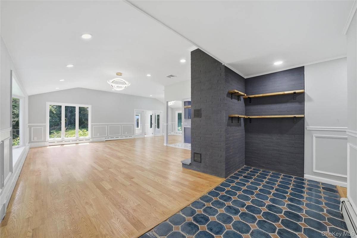 Entry foyer featuring hexagonal floor tiling, leading to a spacious living area with wood-finish flooring and a hallway to the rest of the main floor.