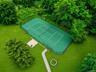 Private tennis court/basketball court with green hard-surface playing area and perimeter fencing
