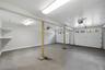 Spacious two-car garage featuring a concrete floor, white walls, and built-in shelving