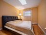 Bedroom featuring a skylight, wood-finish flooring, and a window with white trim