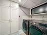 Laundry area with white paneled cabinetry, light blue wall tile, and frosted glass window