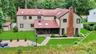 Expansive rear exterior featuring a red shingle roof with skylights, a screened porch, and a large paver patio