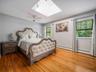 Room featuring hardwood flooring, a ceiling fan, and a skylight with integrated track lighting